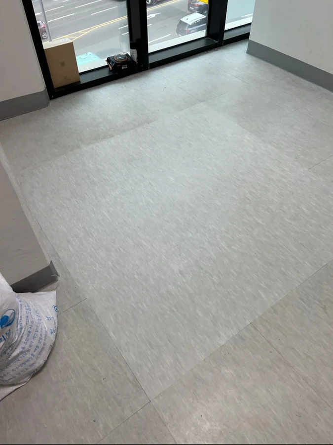 같은 창가 회색 바닥, 오른쪽 아래에 포대가 있고 바닥 중앙에 밝은 사각 영역이 보이는 모습